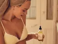 Mujer con toalla en la cabeza sostiene un frasco de aceite de coco, ideal para el cuidado de la piel y el cabello.