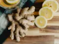 Jengibre y rodajas de limón sobre tabla de madera. Descubre los jengibre beneficios para la mujer, ideal para una bebida revitalizante.