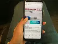 Mano sosteniendo un teléfono que muestra un anuncio de "kit para engravidar" y un test de embarazo. La maca peruana en cápsulas puede ayudar a quienes buscan el embarazo.