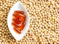 Cápsulas de lecitina de soja en un cuenco blanco sobre semillas de soja. La lecitina de soja tiene propiedades beneficiosas para la menopausia.