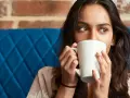 Mujer con taza blanca, quizás probando una bebida sin cafeína para superar la abstinencia de cafeína.