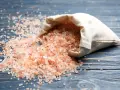 Sal del Himalaya derramada de una bolsa, con sus beneficios y contraindicaciones en mente.
