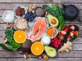 Salmón, bayas, aguacate, espinacas y cúrcuma son algunos de los alimentos antienvejecimiento que se muestran en esta composición sobre madera.