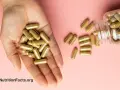 Una mano sostiene cápsulas doradas. Una botella volcada derrama más cápsulas. ¿Se puede tomar ginseng y maca a la vez?