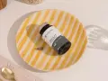 Un frasco de Shilajit y una cápsula sobre un plato rayado. Descubre para qué sirve el shilajit y cómo puede beneficiar tu sistema nervioso e inmunológico.