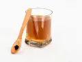 Vaso con bebida dorada y cuchara de madera con shilajit. Descubre los shilajit beneficios para la mujer.