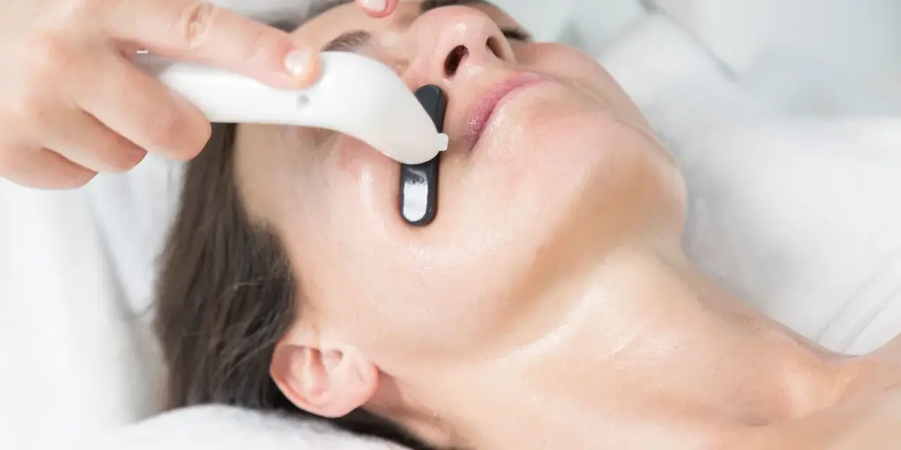 Una persona recibe un tratamiento facial en casa con un dispositivo que emite luz.