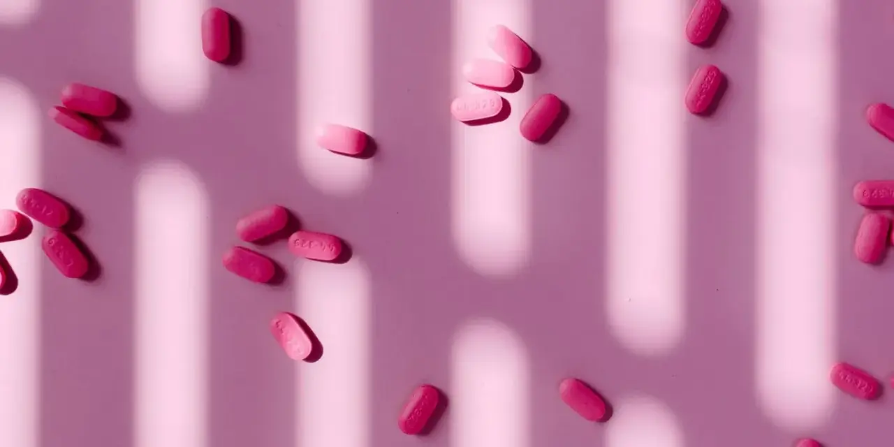 Pastillas rosas esparcidas, algunas con la inscripción "44-329". ¿Paracetamol o ibuprofeno para la regla?