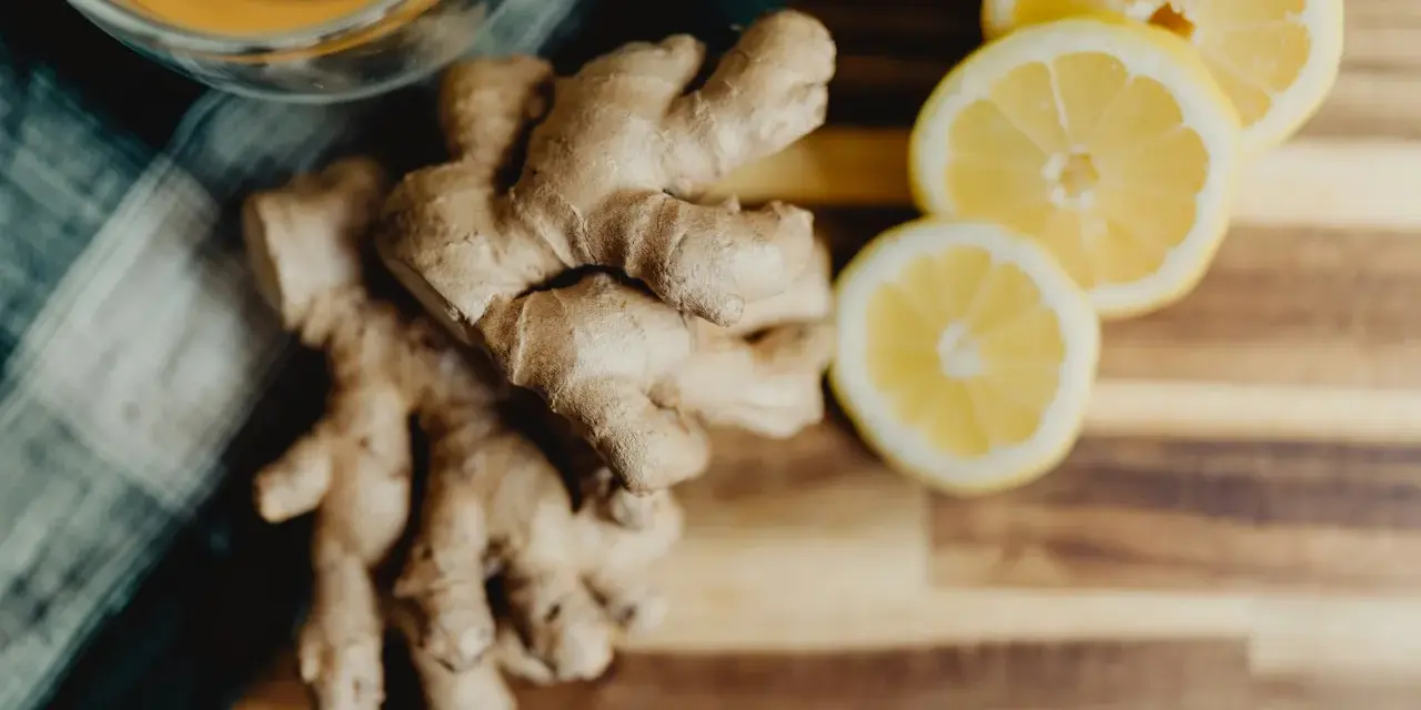 Jengibre y rodajas de limón sobre tabla de madera. Descubre los jengibre beneficios para la mujer, ideal para una bebida revitalizante.