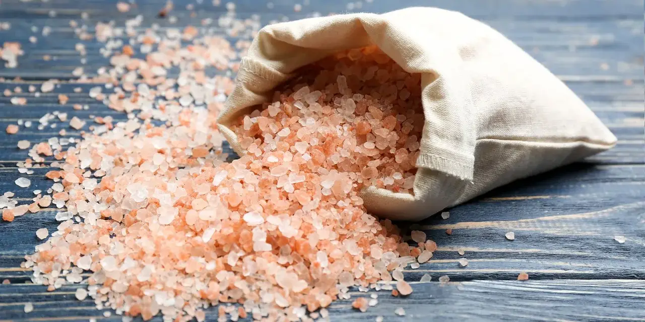 Sal del Himalaya derramada de una bolsa, con sus beneficios y contraindicaciones en mente.