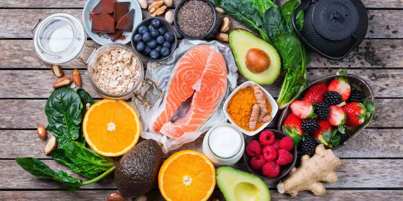 Salmón, bayas, aguacate, espinacas y cúrcuma son algunos de los alimentos antienvejecimiento que se muestran en esta composición sobre madera.
