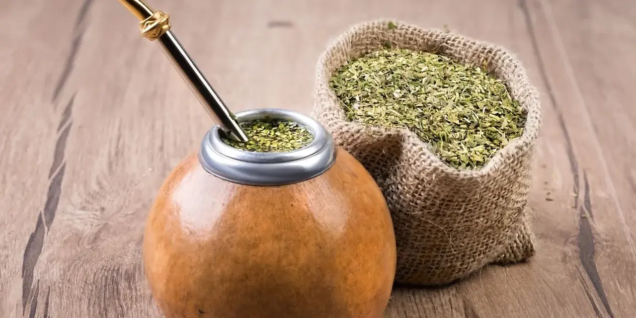 Mate listo para disfrutar, con su bombilla dorada y una bolsa de yerba, destacando las propiedades del mate.