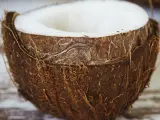 Mitad de coco con pulpa blanca visible. La cáscara fibrosa y marrón resalta las propiedades del coco, un tesoro tropical.