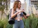 Mujer sonriente con esterilla de yoga y botella de agua. La vitamina B6 para qué sirve en mujeres es clave para su bienestar.