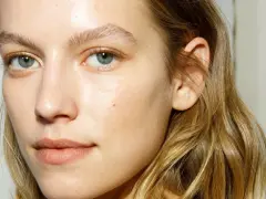 Rostro de mujer con piel luminosa y húmeda, como si acabara de usar bruma facial para que sirve la bruma facial, realzando su belleza natural.