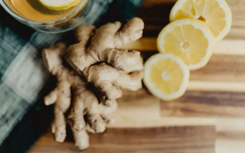 Jengibre y rodajas de limón sobre tabla de madera. Descubre los jengibre beneficios para la mujer, ideal para una bebida revitalizante.