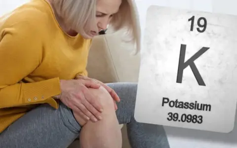 Mujer con dolor de rodilla, posible síntoma de falta de potasio. Se muestra la tabla periódica con el símbolo K.