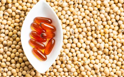 Cápsulas de lecitina de soja en un cuenco blanco sobre semillas de soja. La lecitina de soja tiene propiedades beneficiosas para la menopausia.
