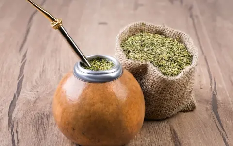 Mate listo para disfrutar, con su bombilla dorada y una bolsa de yerba, destacando las propiedades del mate.