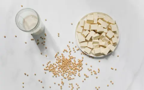 Tofu en cubos, leche de soja y semillas de soja. La nattokinase que es, se deriva de la soja fermentada.
