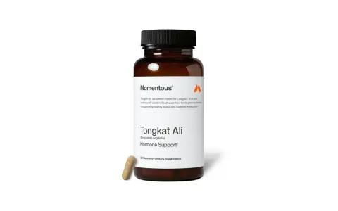 Frasco de suplemento Momentous con etiqueta "Tongkat Ali" para apoyo hormonal. Una cápsula yace al lado.