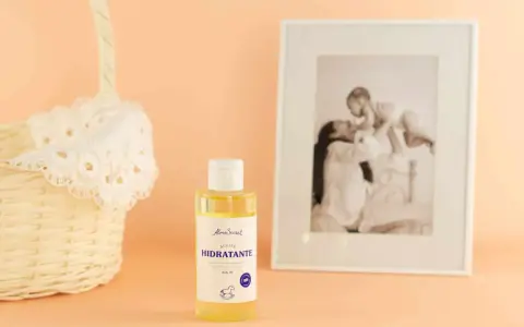 Aceite hidratante de almendras, ideal para el cuidado de la piel durante el embarazo. Junto a una cesta y un marco con foto familiar.
