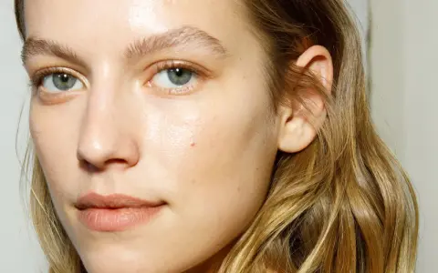 Rostro de mujer con piel luminosa y húmeda, como si acabara de usar bruma facial para que sirve la bruma facial, realzando su belleza natural.