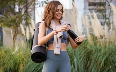 Mujer sonriente con esterilla de yoga y botella de agua. La vitamina B6 para qué sirve en mujeres es clave para su bienestar.