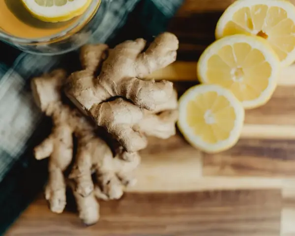 Jengibre y rodajas de limón sobre tabla de madera. Descubre los jengibre beneficios para la mujer, ideal para una bebida revitalizante.