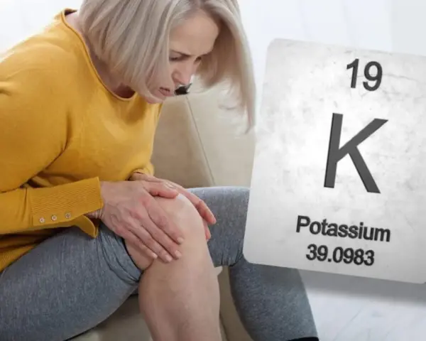 Mujer con dolor de rodilla, posible síntoma de falta de potasio. Se muestra la tabla periódica con el símbolo K.