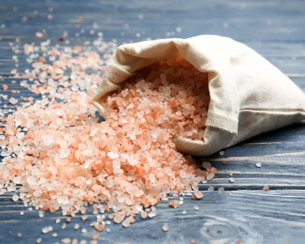 Sal del Himalaya derramada de una bolsa, con sus beneficios y contraindicaciones en mente.