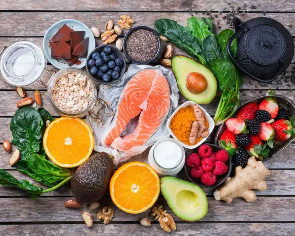 Salmón, bayas, aguacate, espinacas y cúrcuma son algunos de los alimentos antienvejecimiento que se muestran en esta composición sobre madera.