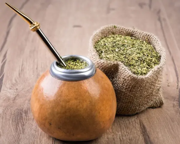 Mate listo para disfrutar, con su bombilla dorada y una bolsa de yerba, destacando las propiedades del mate.