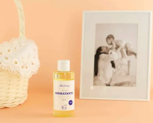 Aceite hidratante de almendras, ideal para el cuidado de la piel durante el embarazo. Junto a una cesta y un marco con foto familiar.