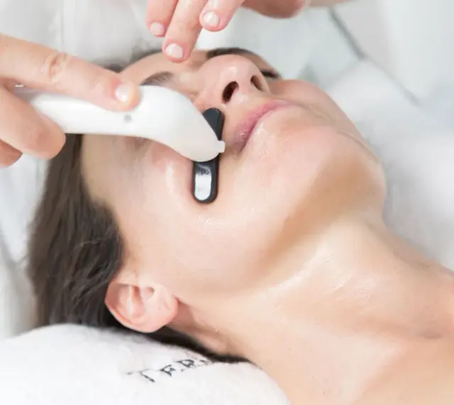 Una persona recibe un tratamiento facial en casa con un dispositivo que emite luz.
