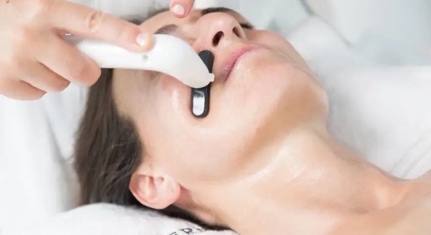 Una persona recibe un tratamiento facial en casa con un dispositivo que emite luz.