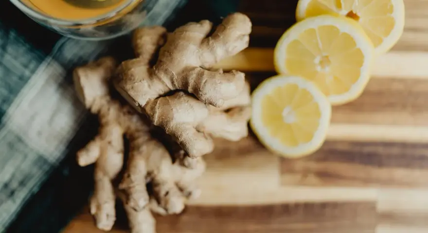 Jengibre y rodajas de limón sobre tabla de madera. Descubre los jengibre beneficios para la mujer, ideal para una bebida revitalizante.