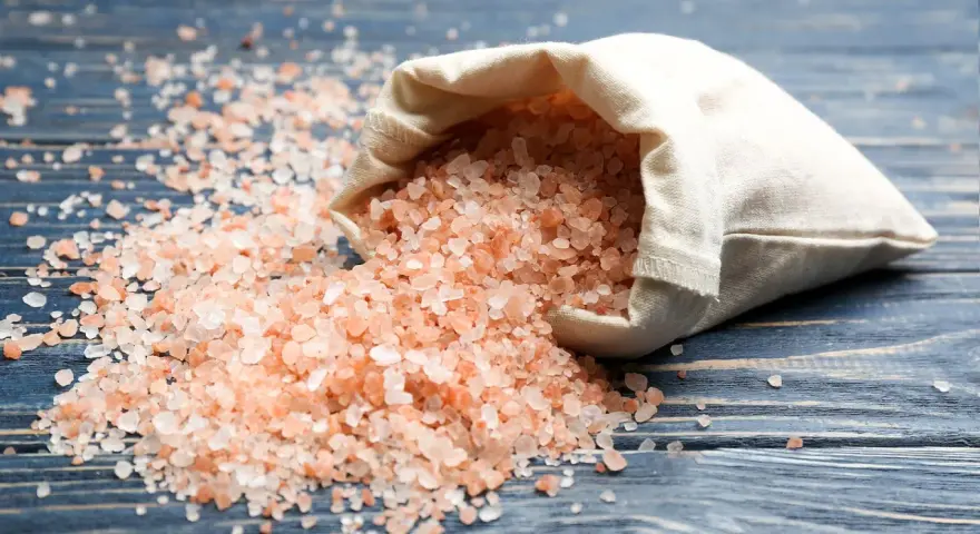 Sal del Himalaya derramada de una bolsa, con sus beneficios y contraindicaciones en mente.