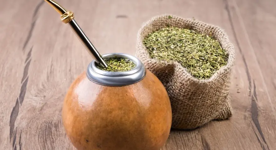 Mate listo para disfrutar, con su bombilla dorada y una bolsa de yerba, destacando las propiedades del mate.