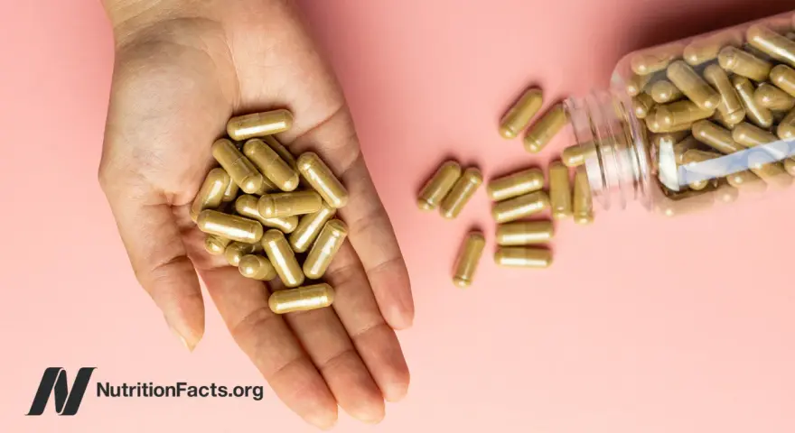 Una mano sostiene cápsulas doradas. Una botella volcada derrama más cápsulas. ¿Se puede tomar ginseng y maca a la vez?