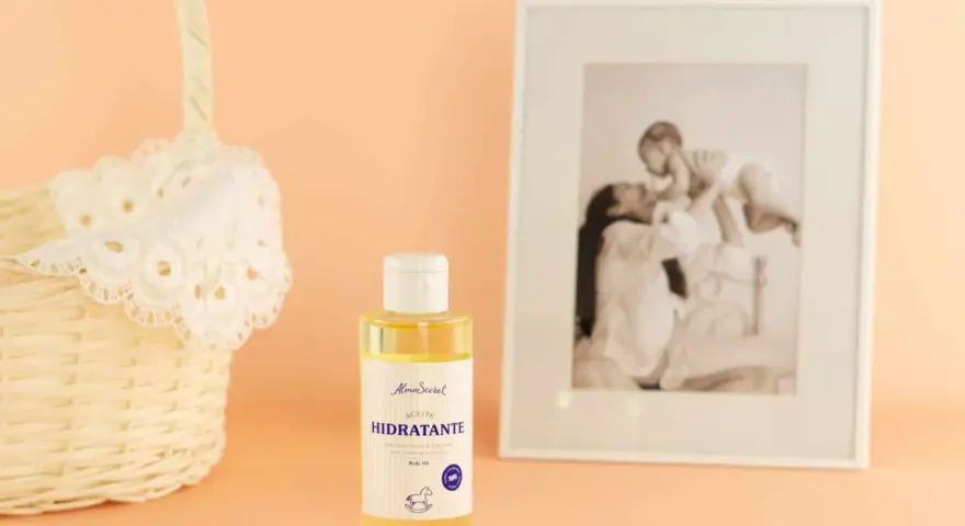 Aceite hidratante de almendras, ideal para el cuidado de la piel durante el embarazo. Junto a una cesta y un marco con foto familiar.