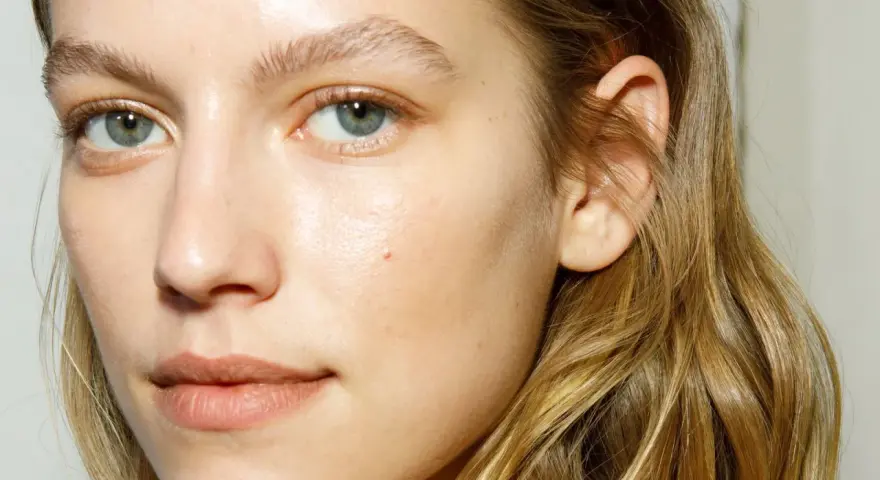 Rostro de mujer con piel luminosa y húmeda, como si acabara de usar bruma facial para que sirve la bruma facial, realzando su belleza natural.