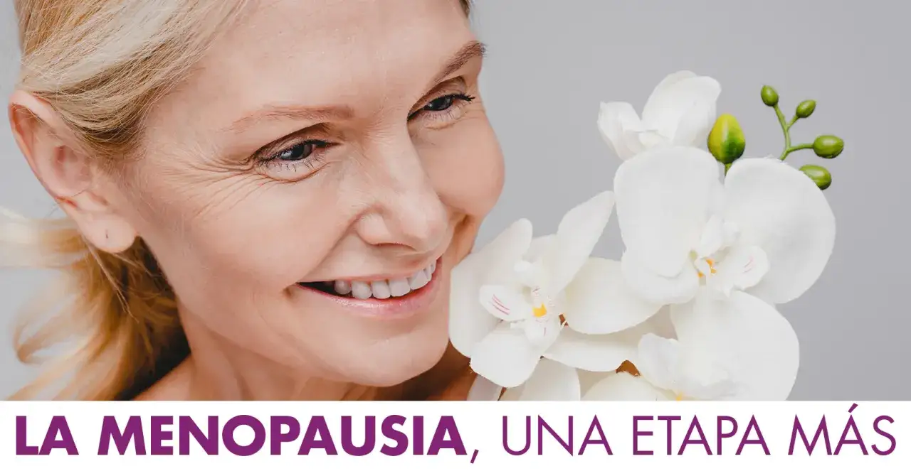 Mujer sonriente con orquídeas blancas. Aborda la menopausia y la falta de estrógenos con remedios naturales.