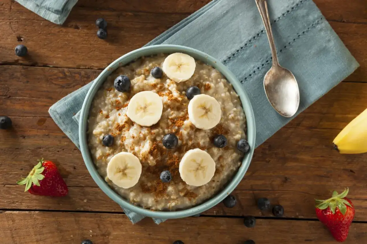 Un tazón de avena con rodajas de plátano, arándanos y canela, un desayuno perfecto para empezar el día con alimentos estimulantes.