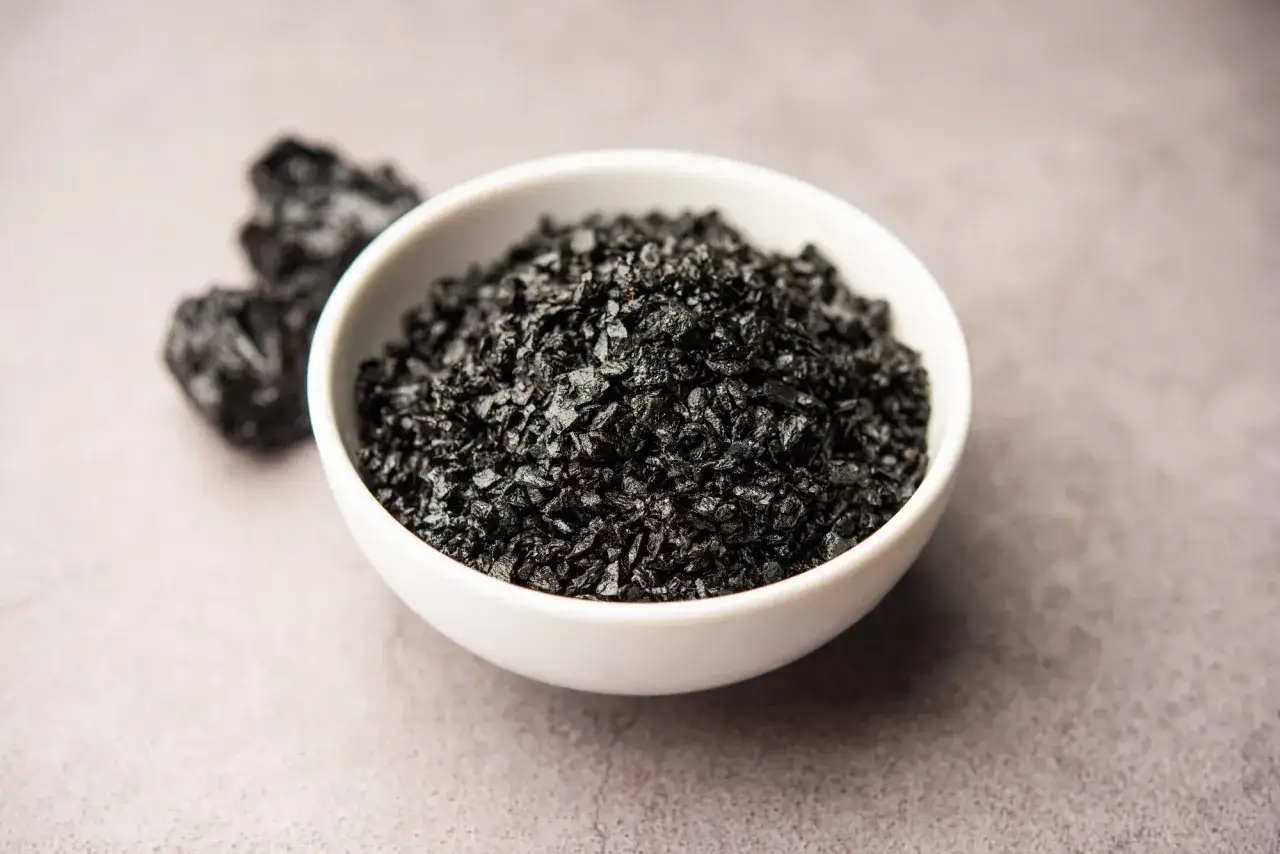 Trozos de shilajit en un cuenco blanco, mostrando para qué sirve este mineral negro y valioso.