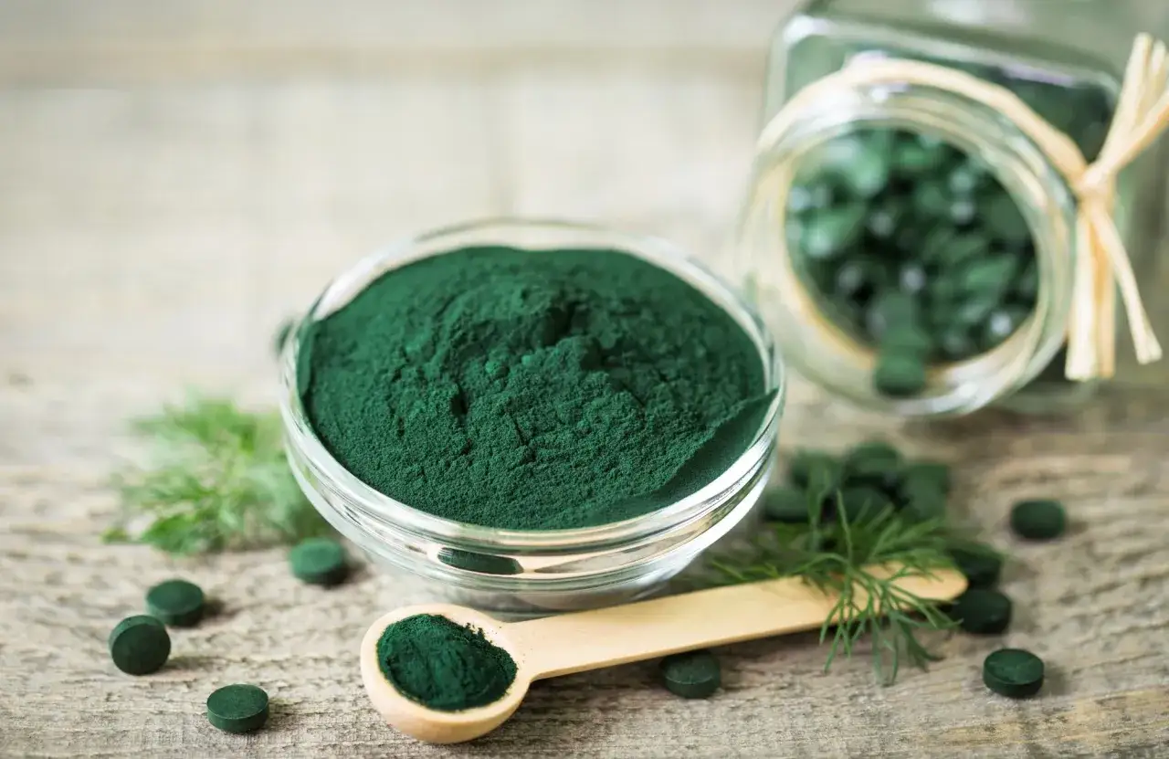 Polvo y pastillas de espirulina verde vibrante. Descubre como tomar espirulina para adelgazar y potenciar tu bienestar.
