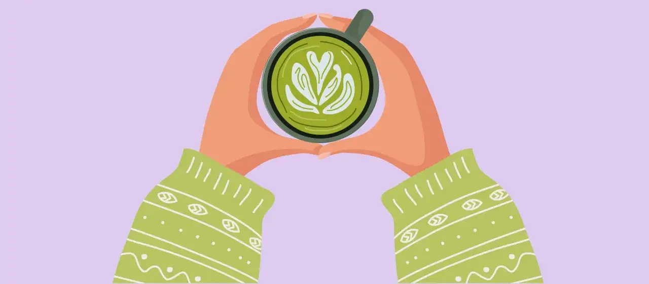 Manos sostienen una taza de matcha con arte latte. ¿EGCG qué es? Es un antioxidante clave en el té verde.