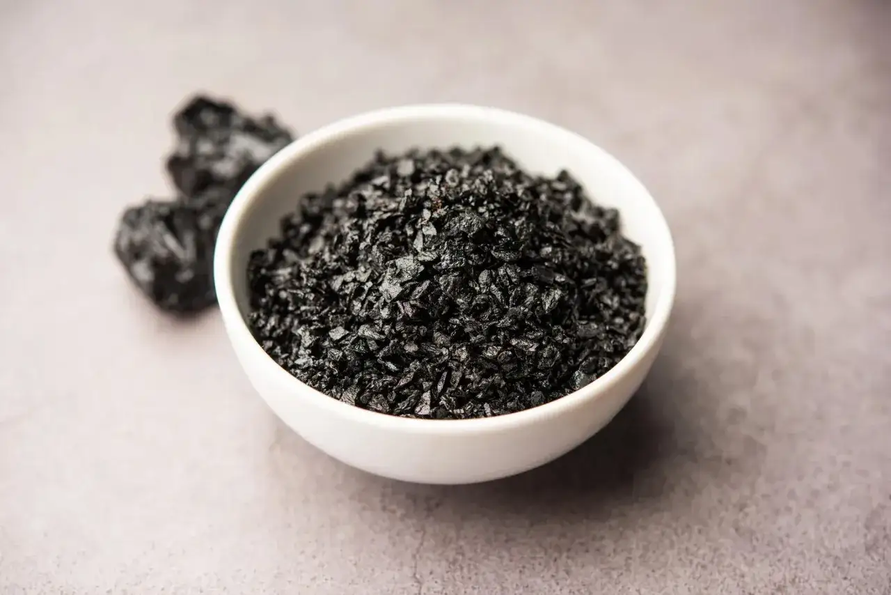 Shilajit en un cuenco blanco, mostrando su textura granular. Se rumorea que el shilajit beneficios para la mujer, aportando vitalidad.