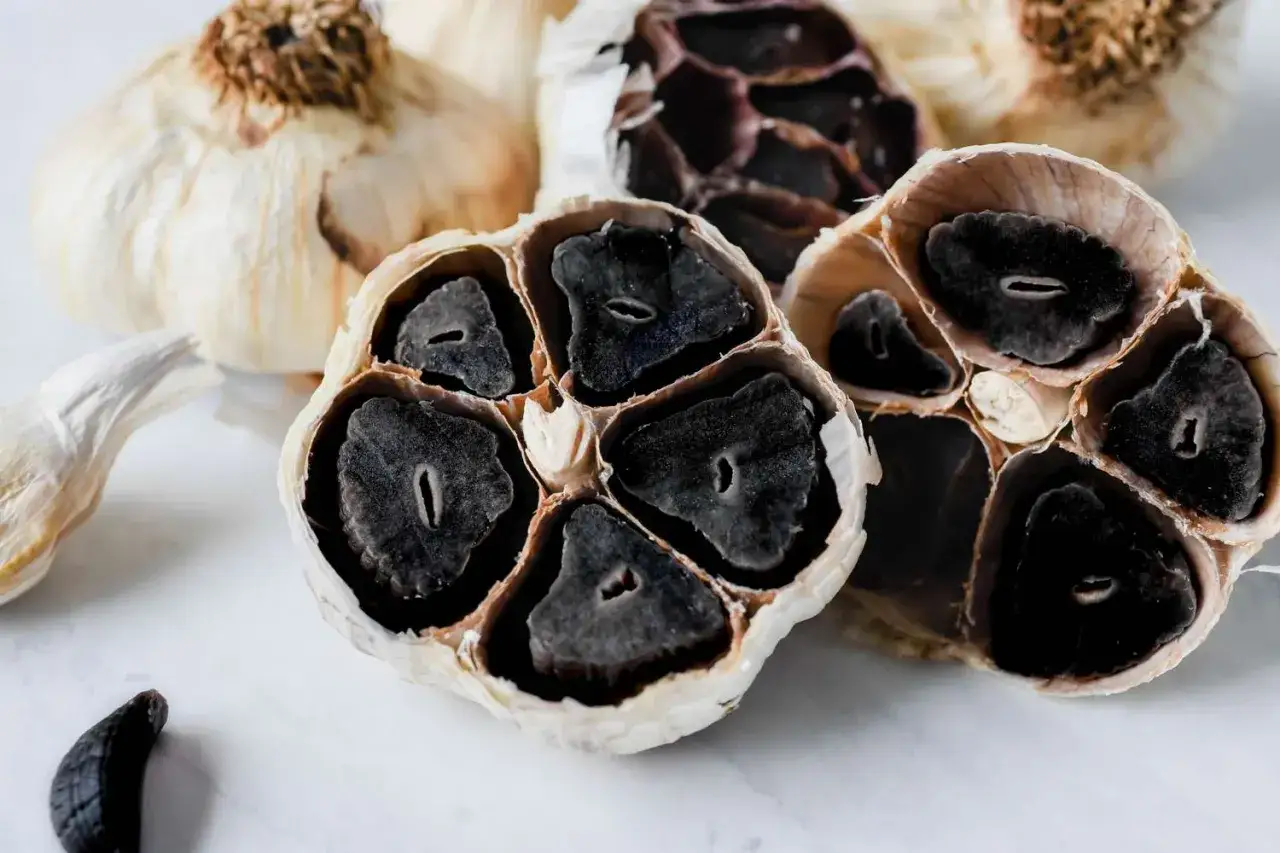 Ajo negro cortado, mostrando dientes negros y blandos. Considera las contraindicaciones del ajo negro antes de consumirlo.