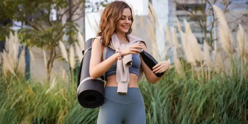Mujer sonriente con esterilla de yoga y botella de agua. La vitamina B6 para qué sirve en mujeres es clave para su bienestar.
